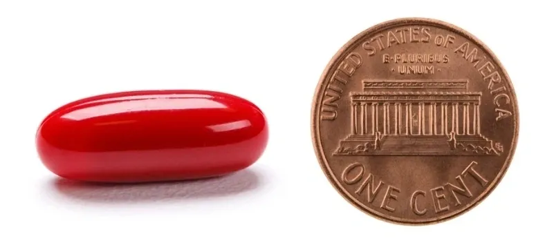 Red pill next to a penny.